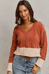 Woman wearing a two-tone sweater with a neutral background
