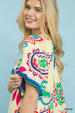 Woman wearing a colorful patterned top against a light blue background