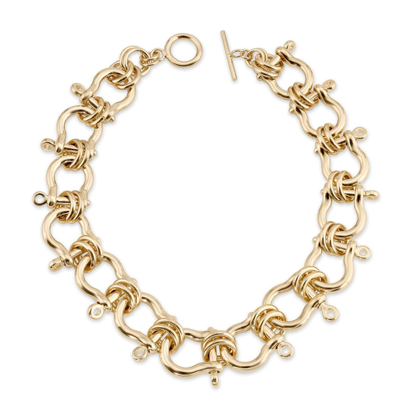 A gold-colored statement necklace with intricate link design, made from recycled brass, showcased against a white background.