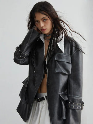 A person modeling a black vegan leather jacket with a stand collar and pockets, paired with a white outfit.