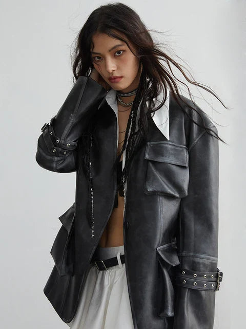 A person modeling a black vegan leather jacket with a stand collar and pockets, paired with a white outfit.