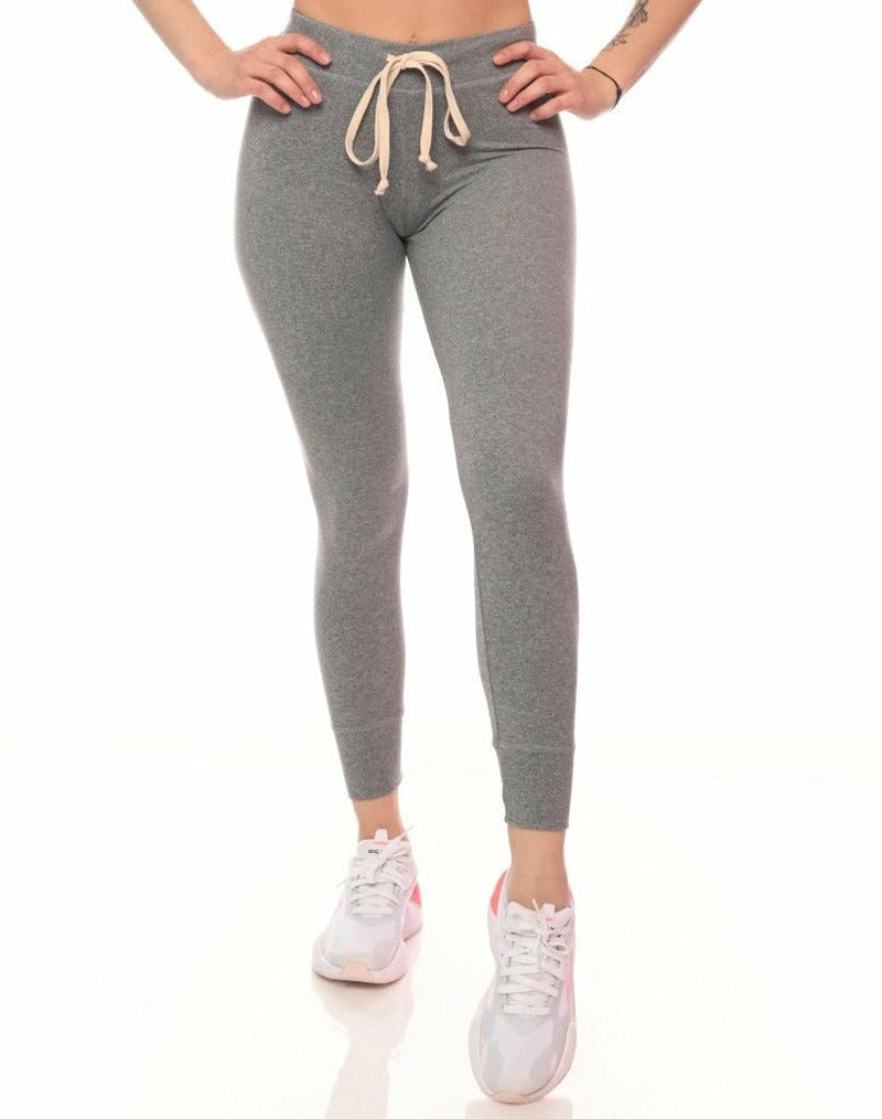 Person wearing gray leggings with a beige drawstring on a white background