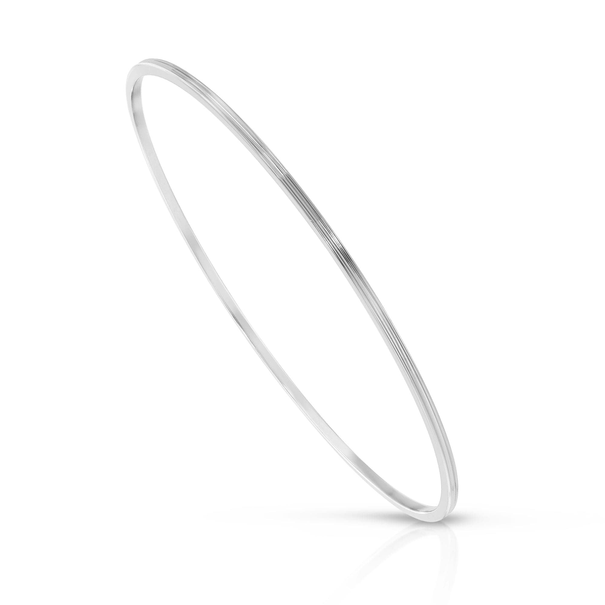 A silver-colored, recycled brass bangle bracelet with a sleek, concave design, displayed against a white background.