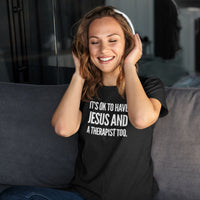 Woman wearing a black t-shirt with text, sitting on a couch.