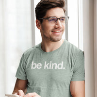 Man wearing a 'be kind' t-shirt in a bright room