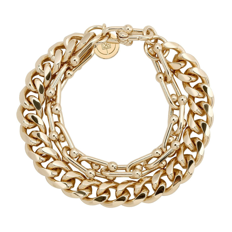 A gold-colored brass bracelet with a rounded curb chain and Margaux U link, displayed against a white background.