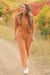 Lady walking on country dirt road wearing Journey Pant set- color is saddle