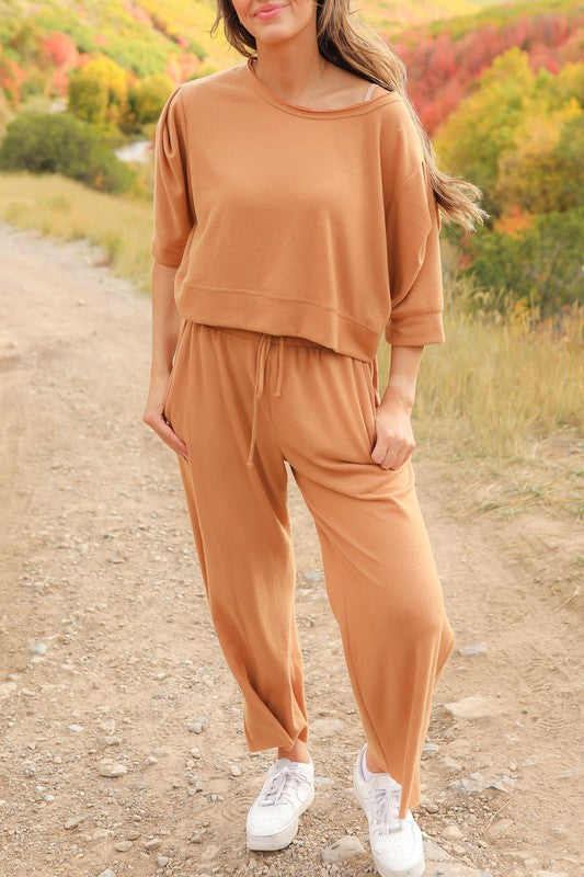 Model posing on the side of a country dirt road showing Journey Pant set-color is saddle