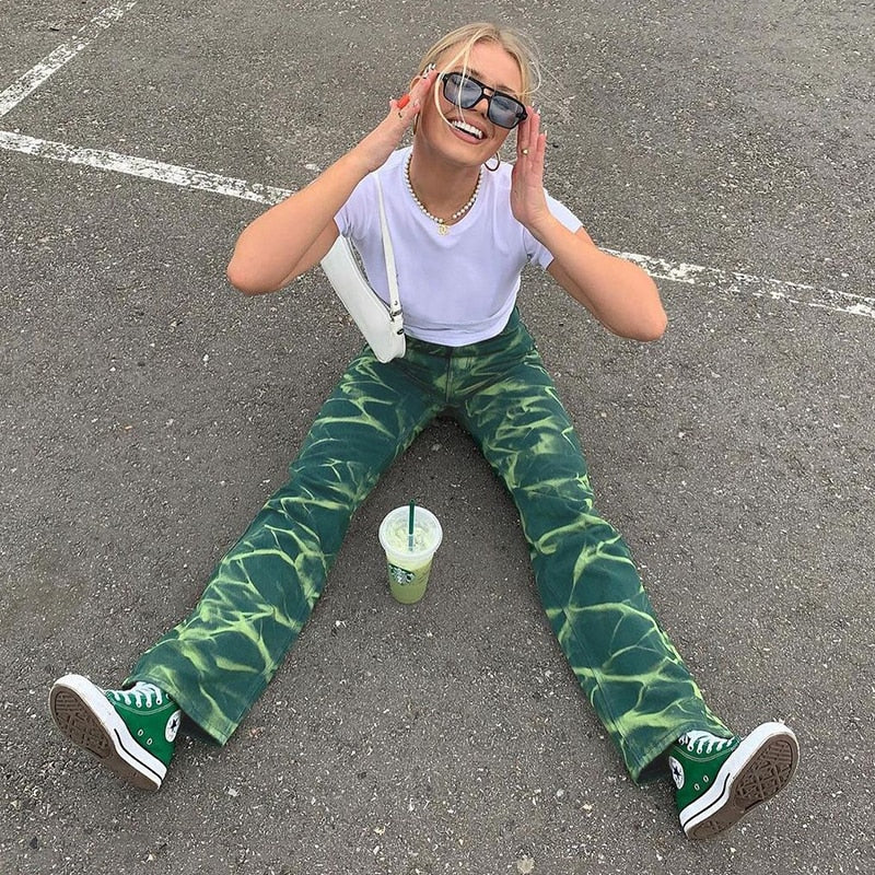Model sitting in a parking lot drinking juice wearing Vintage Acid Wide Leg Jeans